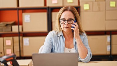 Orta yaşlı İspanyol kadın, iş adamı. Ofiste bilgisayarla konuşuyor.