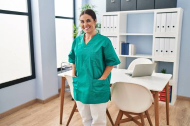 Young beautiful hispanic woman nurse smiling confident standing at clinic