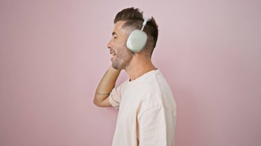 Genç İspanyol bir adam pembe arka planda şarkı söylüyor.