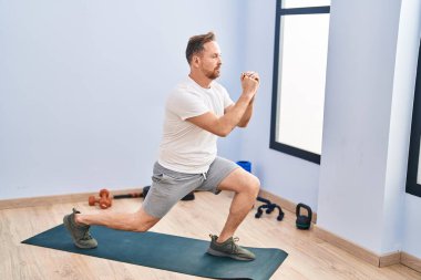 Genç beyaz adam spor merkezinde bacak egzersizi yapıyor.