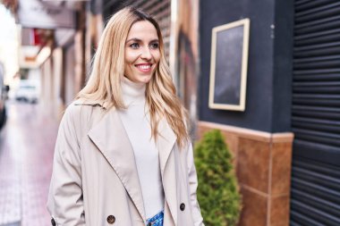 Young blonde woman smiling confident looking to the side at street