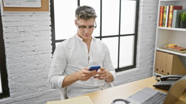 Yakışıklı, rahat, beyaz bir adam ofisteki internet mesaj daktilo işine odaklanıyor. Erkek çalışan akıllı telefon ekranında iş yaşam tarzını gösteriyor.