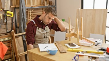 Sakallı yakışıklı genç adam iyi donanımlı bir marangozluk atölyesinde boyun ağrısı çekiyor..