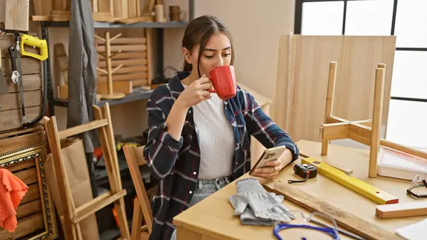 Hispanic Woman Enjoys Coffee While Texting Woodworking Workshop — Stock Photo, Image