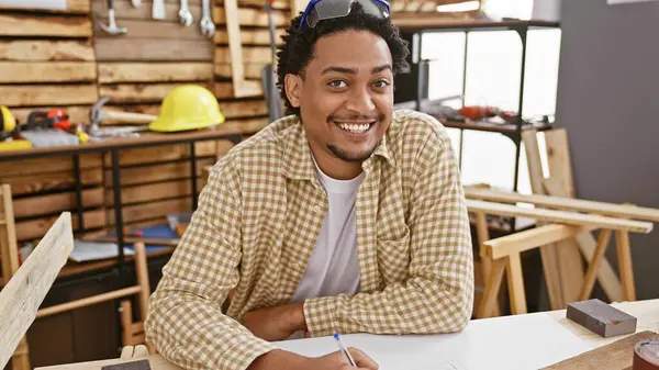 Marangozluk atölyesine gülümseyen kıvırcık saçlı yakışıklı adam mesleğini ve yaratıcılığını yansıtıyor..