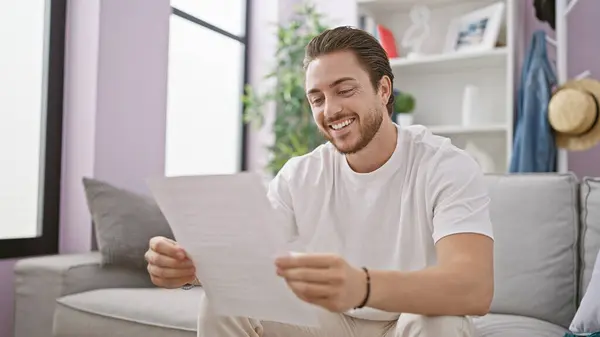 Young Hispanic Man Reading Document Sitting Sofa Smiling Home — Stock Photo, Image