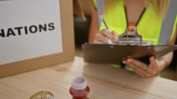 金发女子在仓库组织捐赠活动 重点放在剪贴板 饮料和罐头食品上 — 图库视频影像