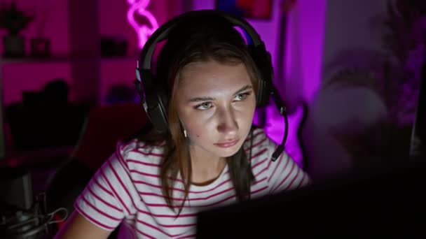 컴퓨터를 보라색 조명에 어두운 룸에서 헤드폰을 집중된 — 비디오