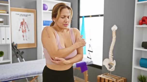 Concerned Hispanic Woman Examines Her Injured Arm Physical Therapy Clinic — Stock Video