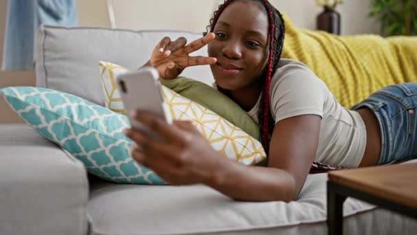 Piękna Afroamerykanka Leżąca Kanapie Domu Radośnie Podejmująca Zwycięskie Selfie Swoim — Wideo stockowe