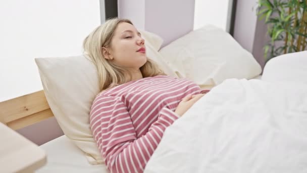 Pembe Çizgili Pijamalı Genç Sarışın Bir Kadın Aydınlık Bir Yatak — Stok video