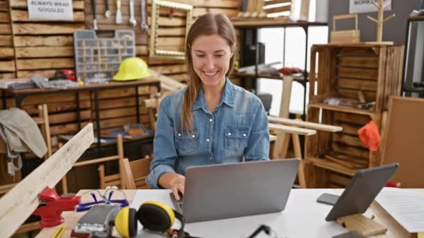 Een Lachende Vrouw Die Een Laptop Gebruikt Een Drukke Timmerwerkplaats — Stockvideo