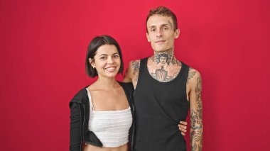 Güzel çift gülümsüyor. Birbirlerine sarılıyorlar. İzole kırmızı arka planda.