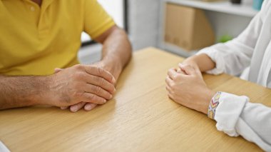 Birlik içinde, İspanyol erkek ve kadın el ele tutuşuyor, birlikte oturma odasındaki masada oturuyorlar anlamlı bir kapalı oturum için.