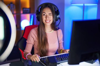 Video oyunları oynayan genç İspanyol kadın kameraya seksi bir ifadeyle bakıyor, neşeli ve mutlu bir yüzle.. 