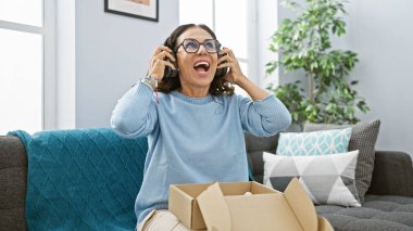 Gözlüklü, kıvırcık saçlı, boks yapmayan ve rahat bir oturma odasında müzik dinleyen heyecanlı bir kadın..