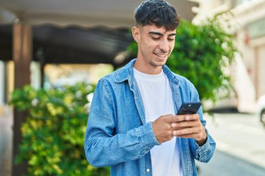 Sokakta akıllı telefon kullanan, kendine güvenen genç bir İspanyol.