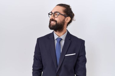 Hispanic man with beard wearing suit and tie looking away to side with smile on face, natural expression. laughing confident. 