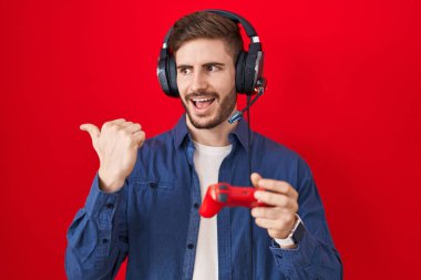 Sakallı, video oyunu oynayan İspanyol bir adam elinde kumandayla baş parmağını kaldırıyor ve ağzı açık gülümsüyor. 