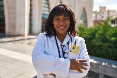 Young beautiful latin woman doctor smiling confident standing with arms crossed gesture at hospital