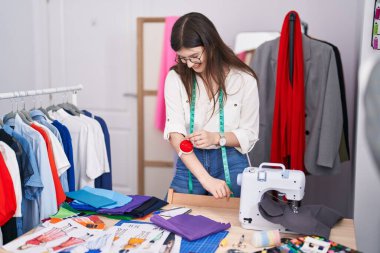 Terzi dükkanında kendine güvenen, gülümseyen beyaz bir kadın.
