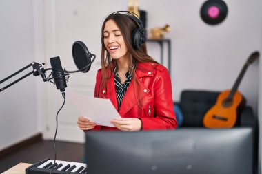 Genç, güzel, İspanyol bir müzisyen müzik stüdyosunda kendine güvenen bir şarkı söylüyor.