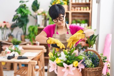 Middle age chinese woman florist cutting plants at flower shop