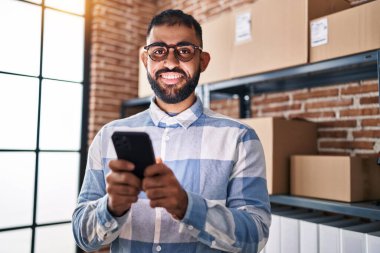 Ofisteki akıllı telefonu kullanan Latin asıllı genç bir iş adamı.