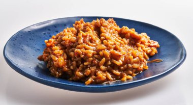 Mavi tabakta servis edilen arsız bir risotto beyaz arka planda, somutlaşmış İtalyan mutfağına karşı..