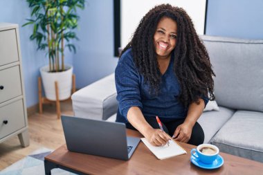 Evde dizüstü bilgisayar kullanan Afrikalı Amerikalı bir kadın.