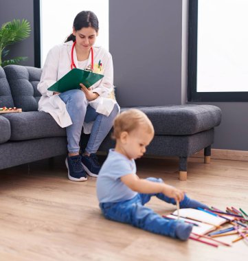 Anne ve oğul doktor evdeki çocuğu muayene eden belgeye yazıyor.