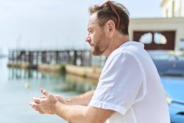 Middle age man looking to the side with serious expression at seaside