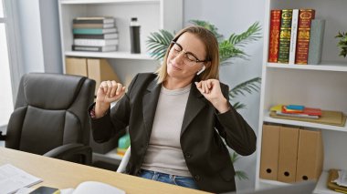Sarışın, bomba gibi patron hanım, genç işkolik işkolik ofisteki en sevdiği melodiyle dans ederken yakalandı, profesyonel görevlerle uğraşırken havayı pozitiflikle coşturuyor.