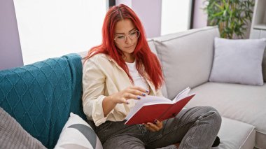 Kitabına dalmış genç, zeki, kızıl saçlı bir kadının büyüleyici portresi. Evdeki kanepesinde rahatça dinleniyor, edebiyat dünyasında kayboluyor.