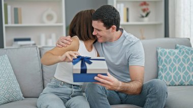 Kanepede oturan güzel çift evde doğum günü hediyesiyle sürpriz yapıyor.