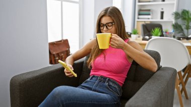 Çalışkan genç İspanyol kadın, işletme müdürü olarak başarıyı yakaladı. Akıllı telefonuyla profesyonel bir mesaj attı. Ofiste canlandırıcı kahvesini içerek.