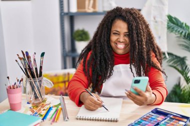 Sanat stüdyosunda akıllı telefon çizimi yapan Afrikalı Amerikalı bir sanatçı.