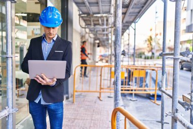 Young man architect using laptop at street