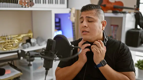 认真的年轻拉丁歌手 一个音响音乐家 全身心地歌唱着他的歌曲 全神贯注于音乐工作室里的旋律 戴着耳机 — 图库照片