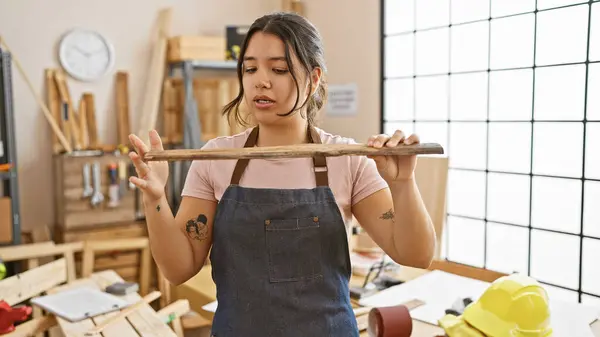Young Hispanic Woman Examines Wooden Plank Bright Carpentry Workshop — Stock Photo, Image