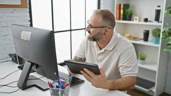 Happy, confident young man enjoying work at office, using touchpad and computer with a smile