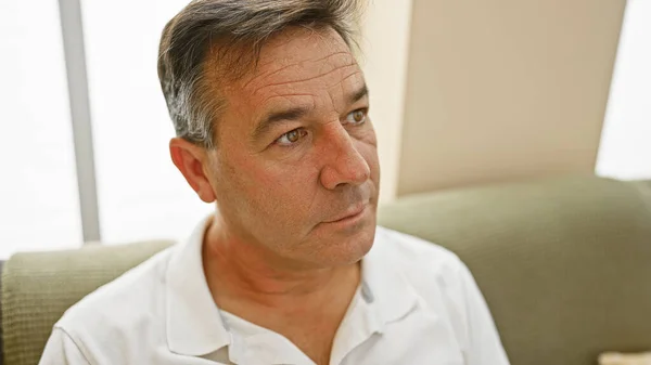 Handsome Middle Aged Man White Shirt Contemplating Indoors Couch Background — Stock Photo, Image