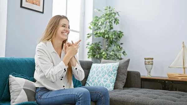 Smiling young woman relaxing on a sofa in a cozy modern living room