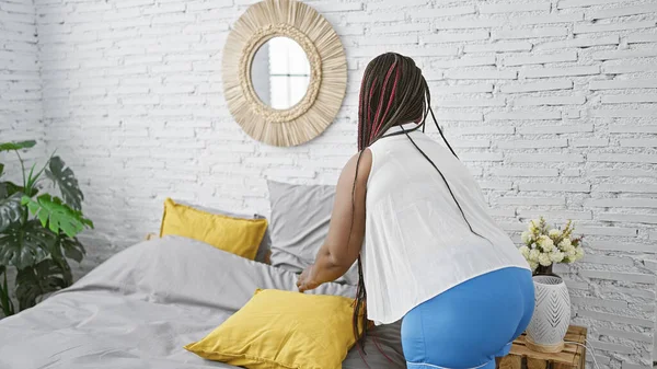 African american woman make bed at bedroom