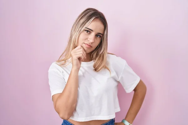 Young Blonde Woman Standing Pink Background Hand Chin Thinking Question — Stok fotoğraf