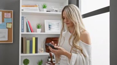 Modern ofiste gülümseyen genç bir kadın, gündelik tarzda, sarışın, profesyonel, çalışan, teknoloji