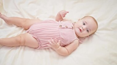 Sevimli küçük bebek, rahatlamış ve rahat, kanepeye uzanmış, battaniyeye gülümsüyor, yeni doğmuş huzurlu bir yaşam tarzının mükemmel bir resmi..