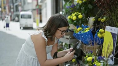 Gözlüklü güzel İspanyol kadın Tokyo sokaklarında canlı çiçekler çekiyor.