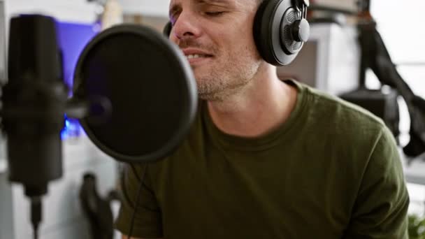 ヘッドフォンと情熱を持って音楽スタジオでマイクに歌うヒスパニック男 — ストック動画