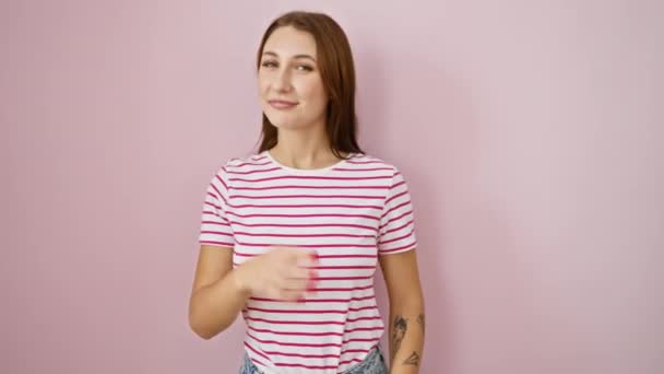 どうした トレンディなストライプTシャツの若くて美しいブルネットの少女は カメラで彼女の指を指差しています 良いバイブと喜びを積極的に吹き飛ばす ピンクの背景に隔離された — ストック動画